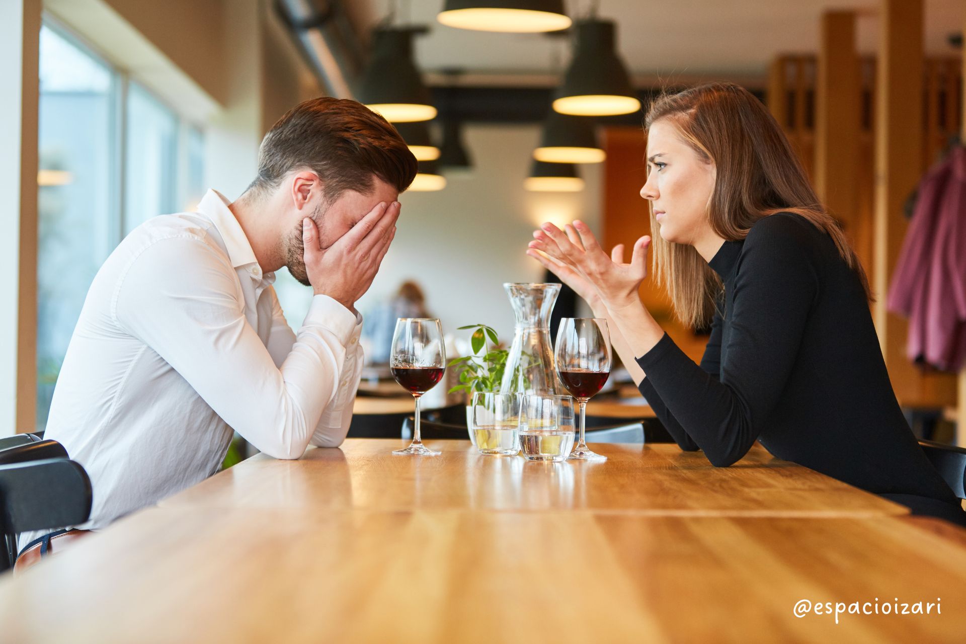 Dos personas conversando en una mesa de un restaurante con copas de vino y agua, reflejando la importancia de la comunicación en las relaciones de pareja. La imagen ilustra un momento de diálogo y conexión, ideal para acompañar un artículo sobre la gestión de los celos y la confianza en una relación.