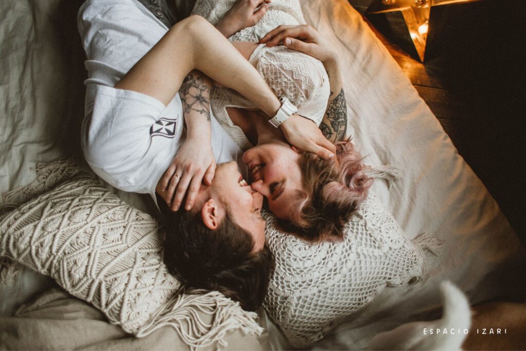 Pareja joven abrazada y sonriendo tumbada en la cama, simbolizando un vínculo que se cuida incluso cuando hay discusiones