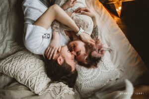 Pareja joven abrazada y sonriendo tumbada en la cama, simbolizando un vínculo que se cuida incluso cuando hay discusiones