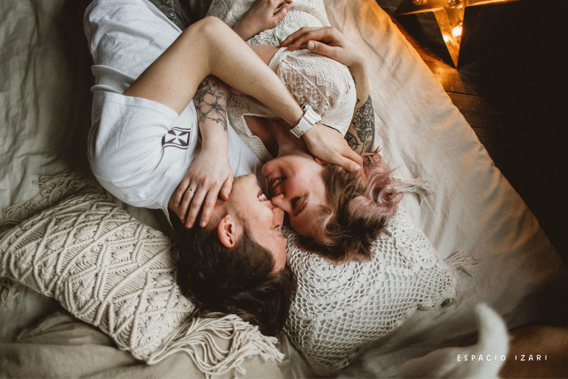 Pareja joven abrazada y sonriendo tumbada en la cama, simbolizando un vínculo que se cuida incluso cuando hay discusiones
